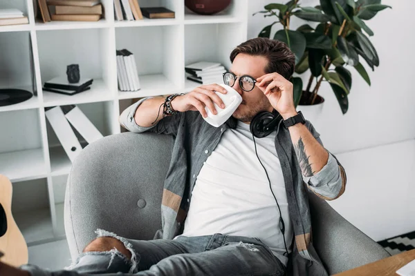 Homme avec écouteurs boire du café — Photo de stock