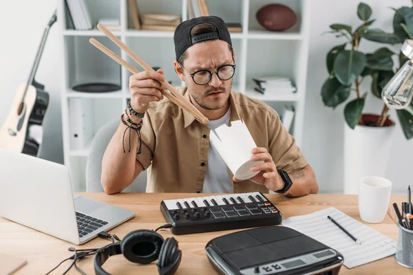 Музыкант ест китайскую еду с барабанными палочками — стоковое фото