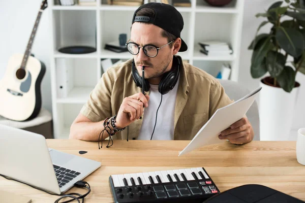 Вдумчивый музыкант смотрит на ноутбук — стоковое фото