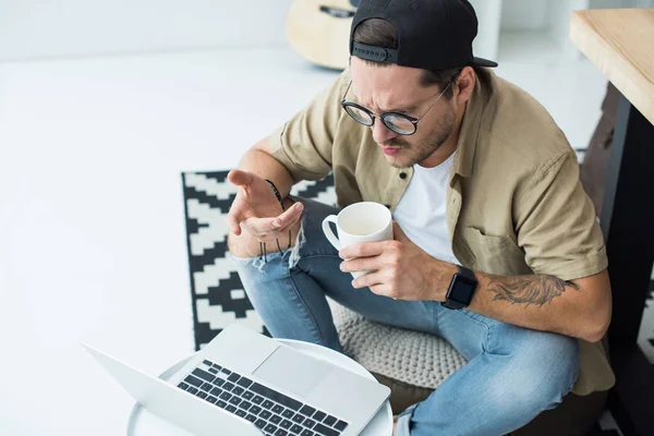 Homem com xícara de café olhando para laptop — Fotografia de Stock