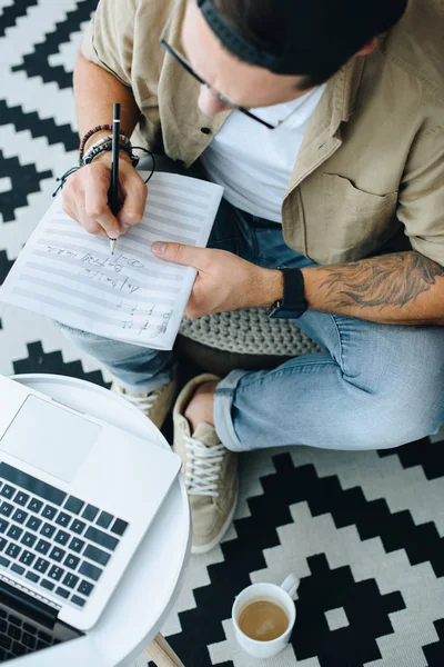 Hombre escribiendo notas y mirando el ordenador portátil - foto de stock