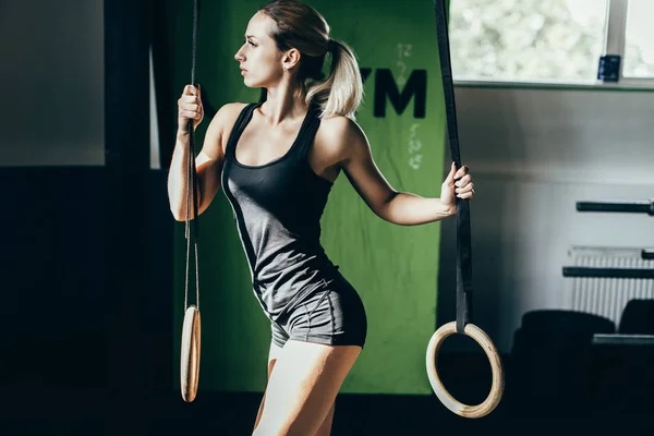 Sportswoman posing with gymnastic rings — Stock Photo