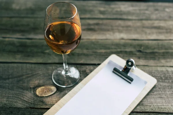 Glass of white wine and clipboard — Stock Photo