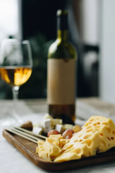 Glass with wine and plate with cheese and grapes — Stock Photo