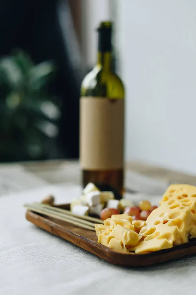 Bottiglia e piatto di vino con formaggio e uva — Foto stock