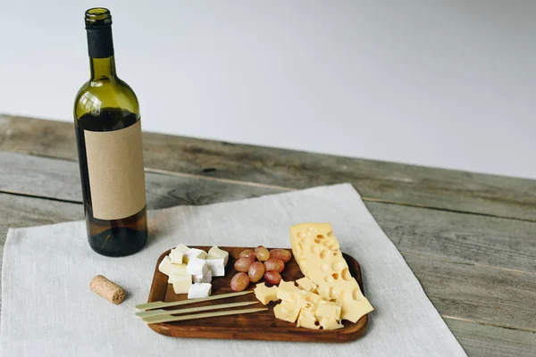 Bottiglia e piatto di vino con formaggio e uva — Foto stock