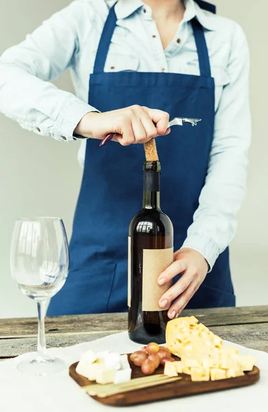 Donna aprendo bottiglia di vino bianco — Foto stock