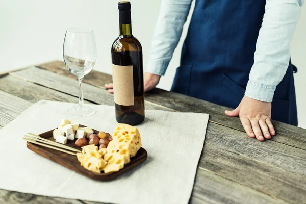 Sommelier debout à table avec bouteille de vin — Photo de stock