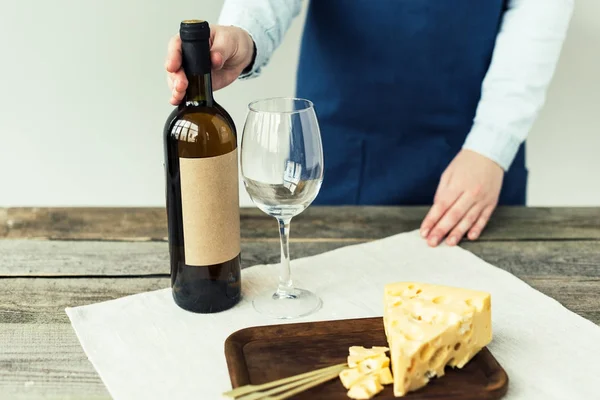 Woman in apron holding bottle of wine — Stock Photo