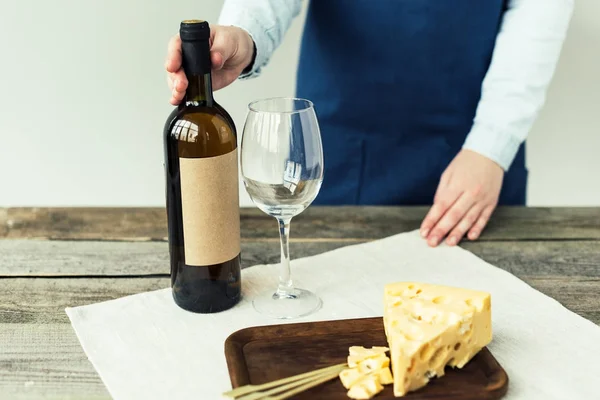 Mujer en delantal sosteniendo botella de vino - foto de stock