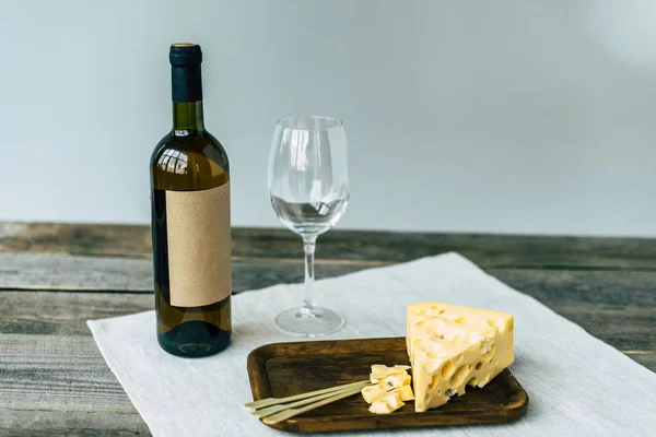 Botella de vino con vaso vacío y queso - foto de stock