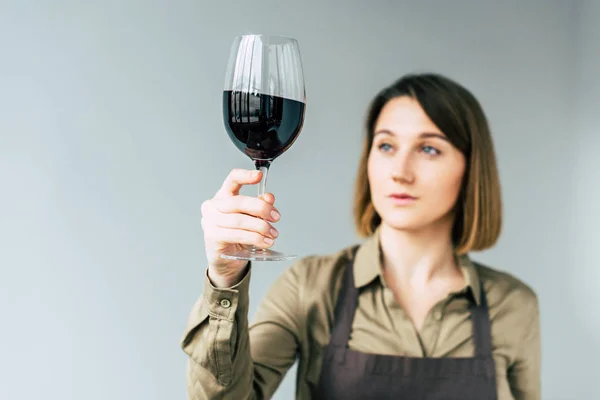 Sommelier femenino examinando el vino tinto - foto de stock