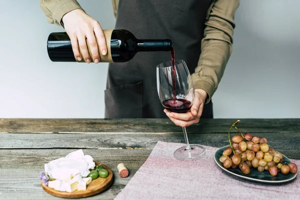 Sommelier versant du vin rouge dans un verre — Photo de stock