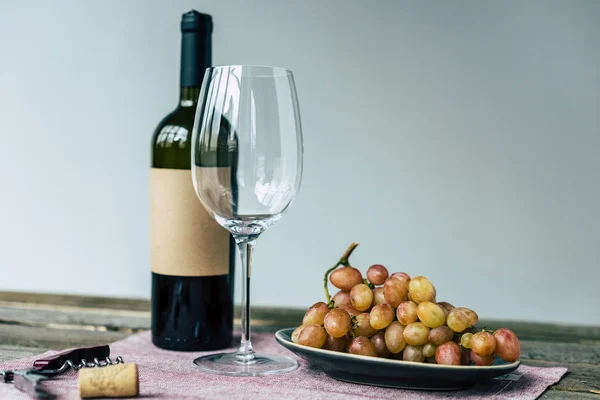 Botella de vino con vaso vacío y uvas - foto de stock