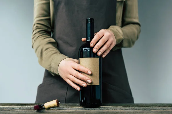 Mujer sosteniendo botella abierta de vino - foto de stock