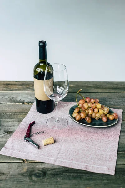 Botella de vino con vaso vacío y uvas - foto de stock