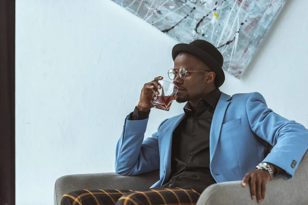 Africano americano uomo in cappello bere whisky — Foto stock