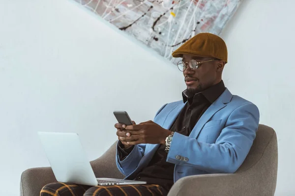 Hombre afroamericano usando portátil y teléfono inteligente - foto de stock