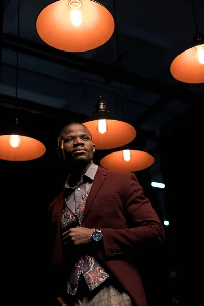Homem elegante no quarto escuro com lâmpadas — Fotografia de Stock
