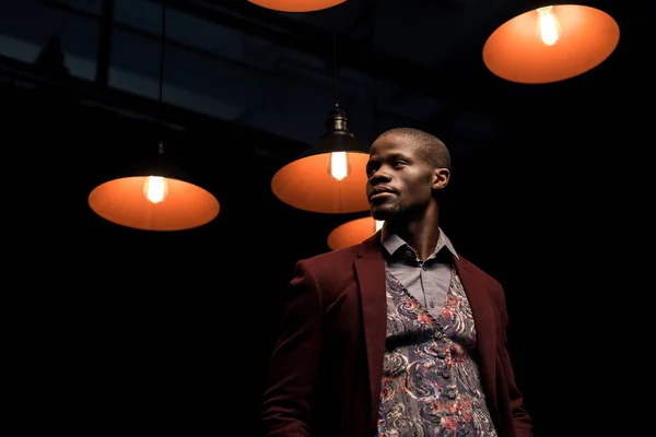 Homme afro-américain dans la chambre noire avec des lampes — Photo de stock