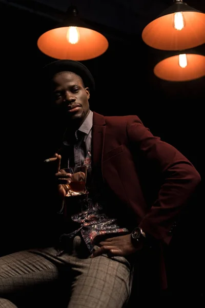 Hombre afroamericano de moda con cigarro y whisky - foto de stock