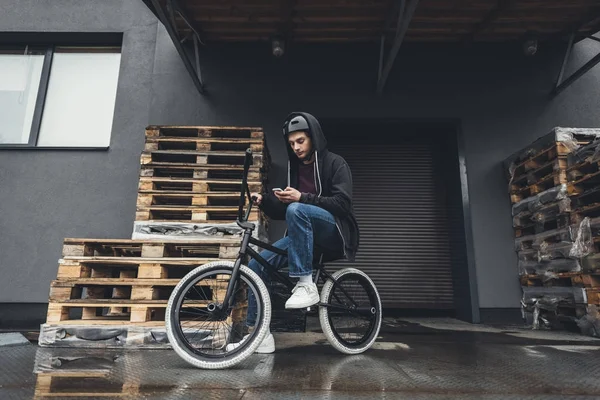 Велосипедист bmx с помощью смартфона — стоковое фото