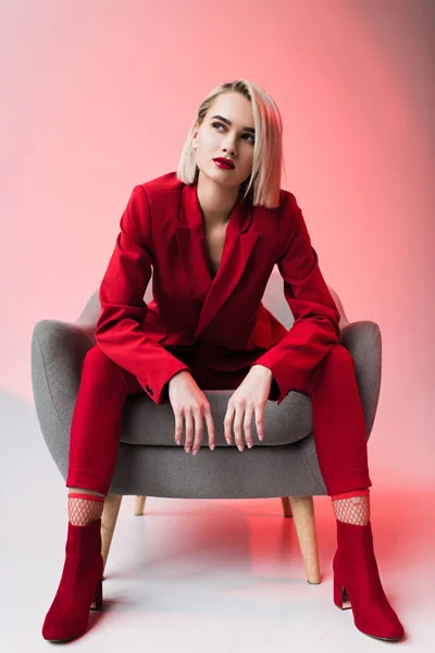 Mujer en ropa roja posando en sillón - foto de stock