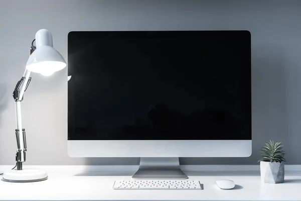Lugar de trabajo con ordenador y lámpara de mesa encendida - foto de stock