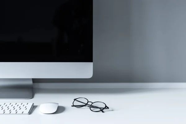 Очки и компьютерная мышь с клавиатурой на рабочем столе — стоковое фото