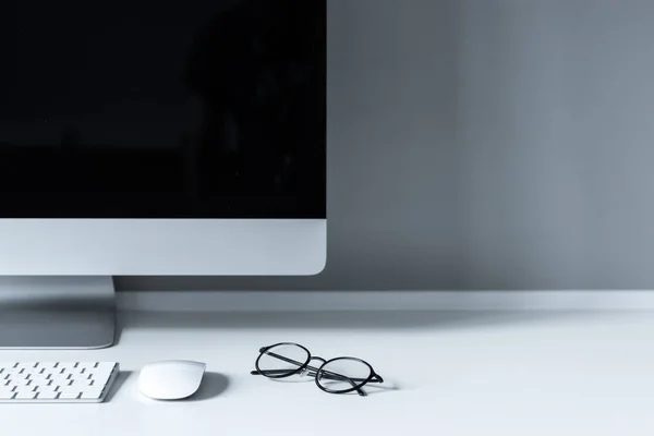 Gafas y ratón de ordenador con teclado en la mesa de trabajo - foto de stock