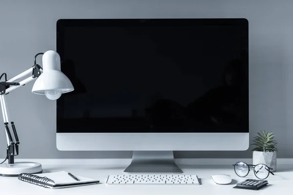 Lugar de trabajo con ordenador, lámpara de mesa y portátil - foto de stock