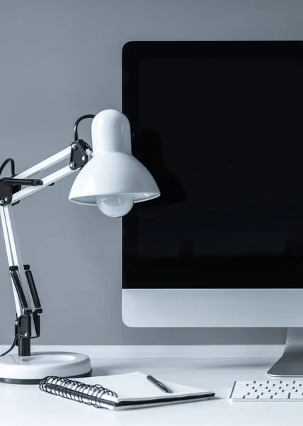 Lampe de table blanche et ordinateur avec écran noir — Photo de stock