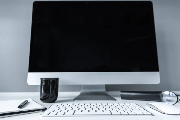 Posto di lavoro con computer, tazza nera e notebook — Foto stock