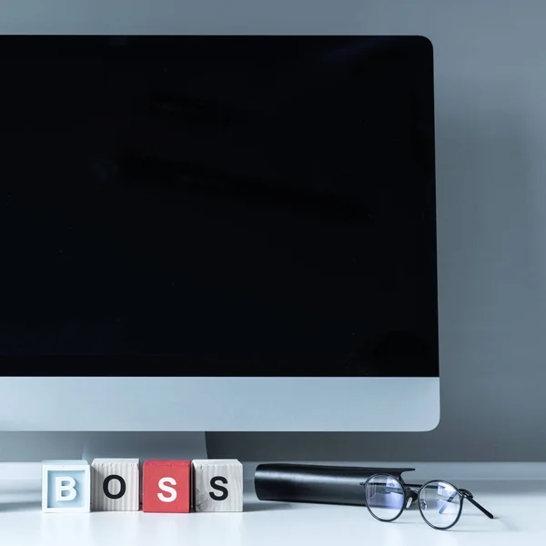 Ordinateur et cubes en bois avec mot Boss sur une table — Photo de stock