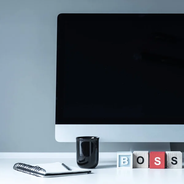 Computer and wooden cubes with word Boss — Stock Photo