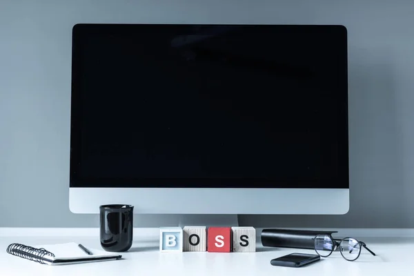 Ordinateur et cubes en bois avec mot Boss sur la table — Photo de stock