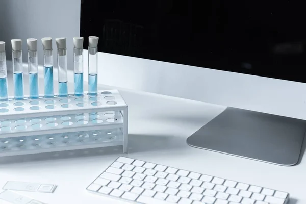 Tubes à essai avec liquide bleu sur la table de travail — Photo de stock
