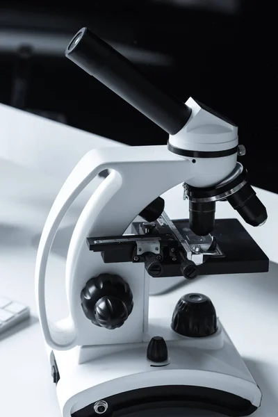 Microscopio blanco y negro en la mesa de trabajo - foto de stock