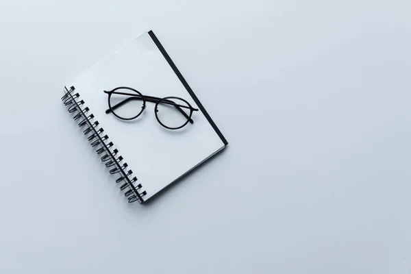 Vista superior de las gafas en cuaderno blanco abierto aislado en blanco - foto de stock