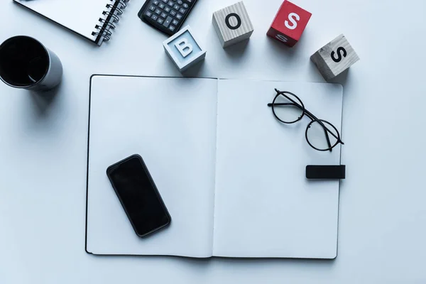 Top view of smartphone and glasses on open notebook — Stock Photo