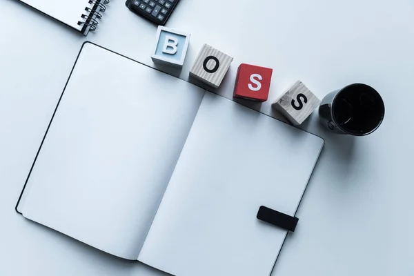 Top view of wooden cubes with word Boss and open notebook — Stock Photo