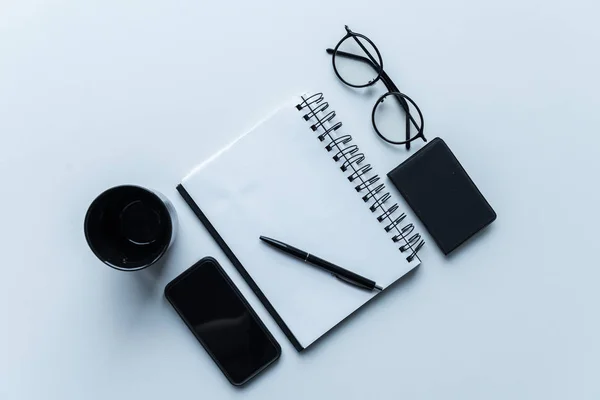 Vue du haut du smartphone et de la tasse avec ordinateur portable ouvert et stylo — Photo de stock