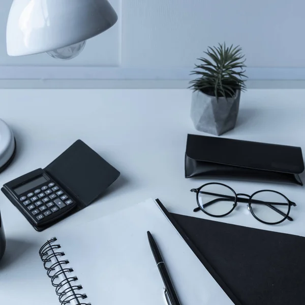 Cuaderno abierto y pluma con calculadora y vasos en la mesa - foto de stock