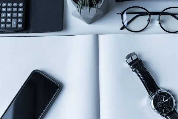 Overhead view of smartphone and watch on open notebook — Stock Photo