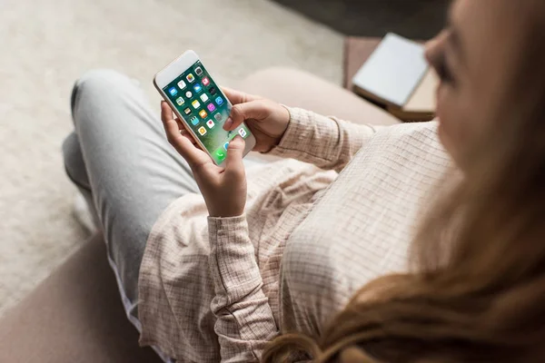 Plan recadré de la femme sur le canapé en utilisant un smartphone avec des applications ios à l'écran — Photo de stock