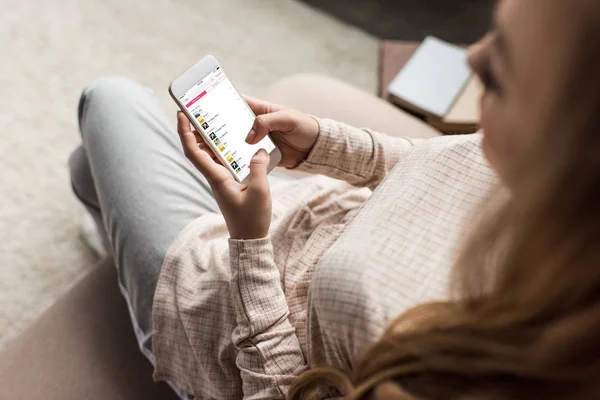 Обрізаний знімок жінка на дивані, за допомогою смартфона з itunes app на екрані — стокове фото