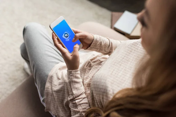 Schnappschuss von Frau auf Couch mit Smartphone und Shazam-App auf dem Bildschirm — Stockfoto
