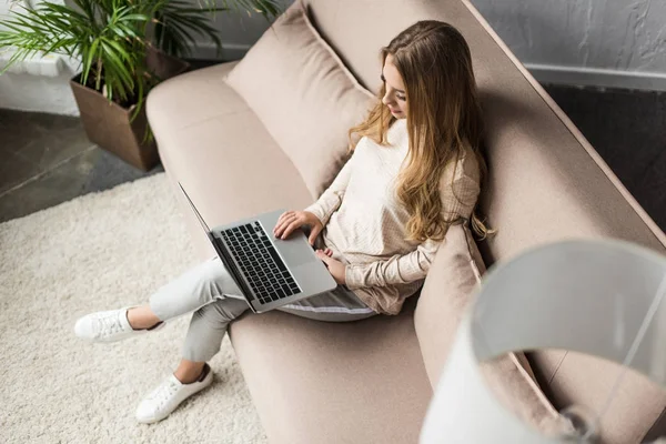 High angle view of young woman working with laptop on sofa — Stock Photo