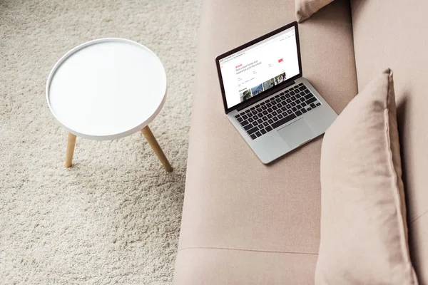 Visão de alto ângulo do laptop em pé no sofá acolhedor com site airbnb na tela — Fotografia de Stock