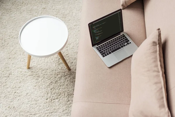 High angle view of programmer laptop with code on screen on cozy couch — Stock Photo